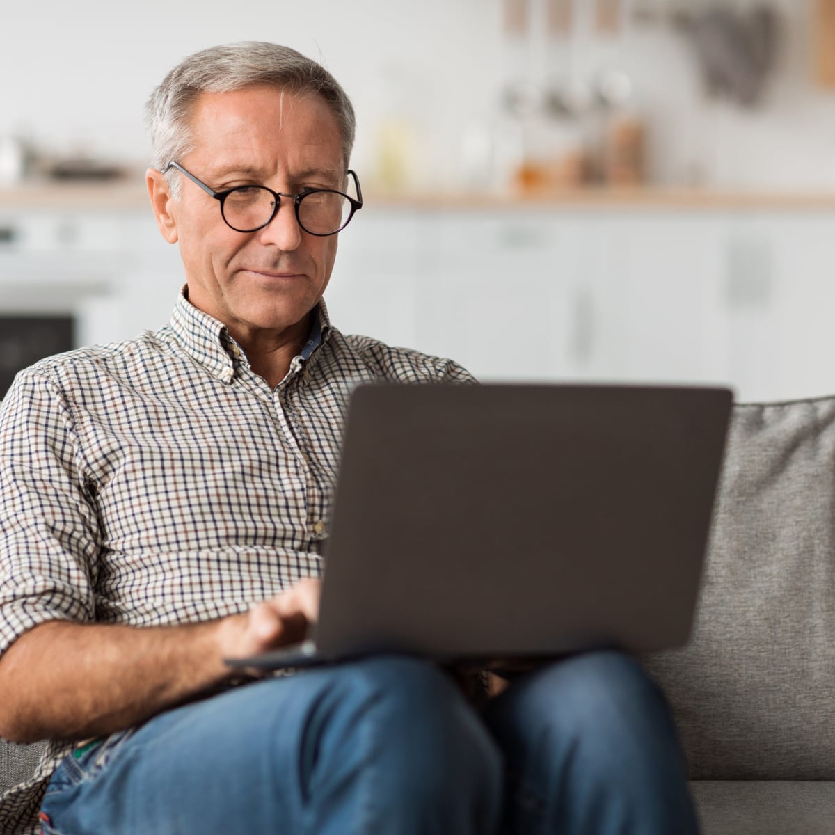 Senior male using a laptop while sitting on a couch